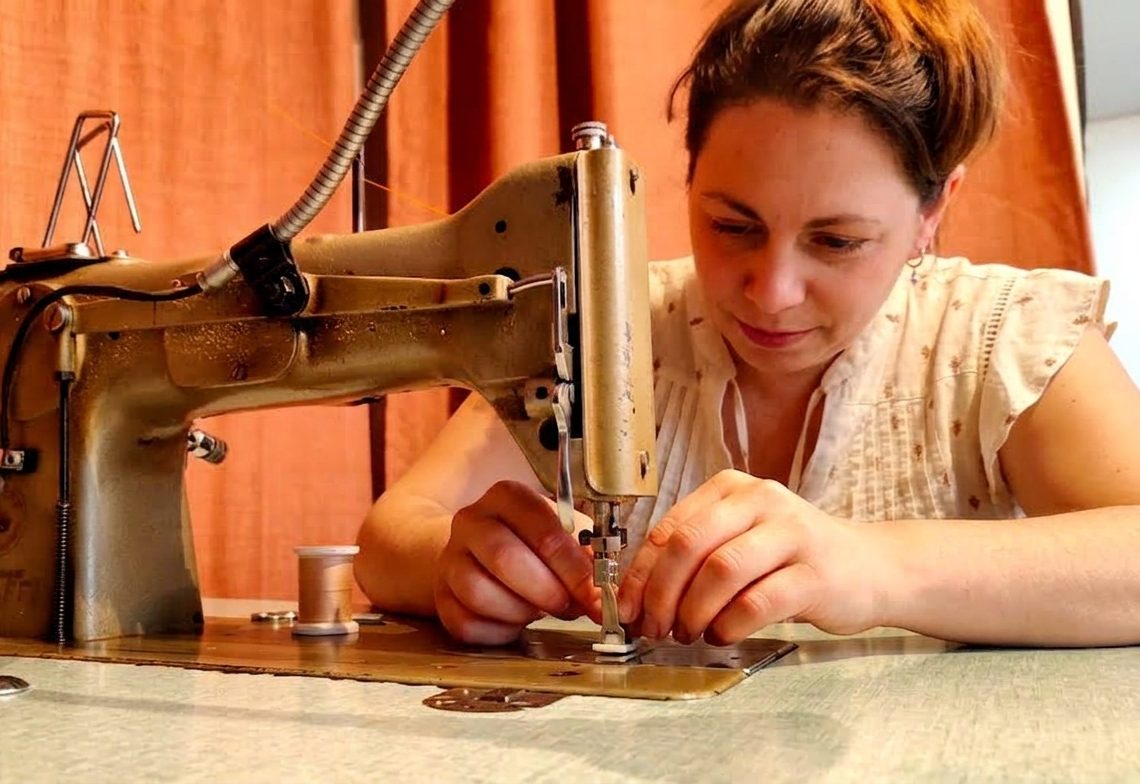 Delphine Rouchon coud une sangle de sandale sur une machine à coudre d'atelier